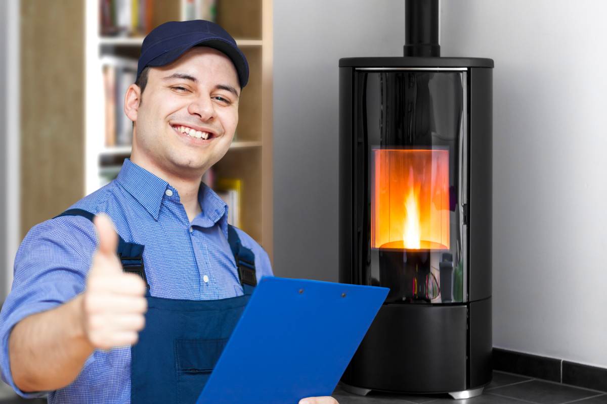 stufa a pellet sullo sfondo ed in primo piano tecnico che fa segno ok