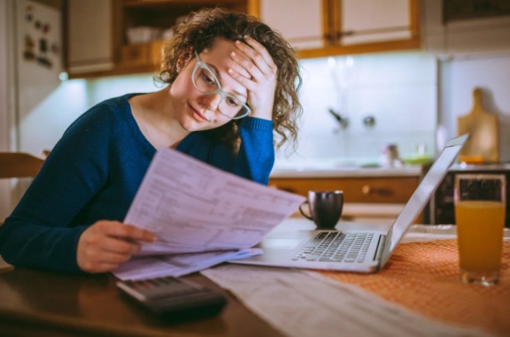 donna che legge un foglio con espressione preoccupata e una mano sulla fronte