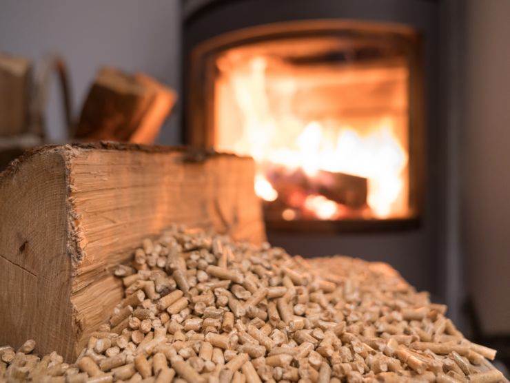 legna e pellet in primo piano, come sfondo una stufa accesa