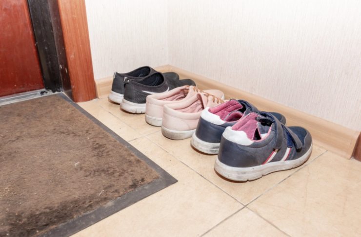 tre paio di scarpe sul pianerottolo davanti alla porta di casa